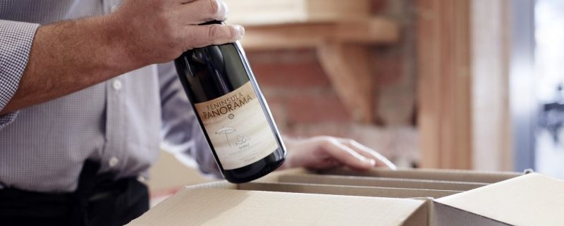 cropped picture of a man packing wine bottle in a cardboard box